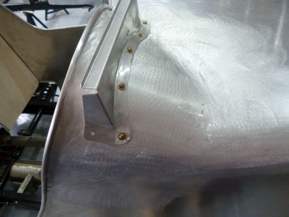 Close view of a curved bare aluminium panel and its fixings during trial fitting.