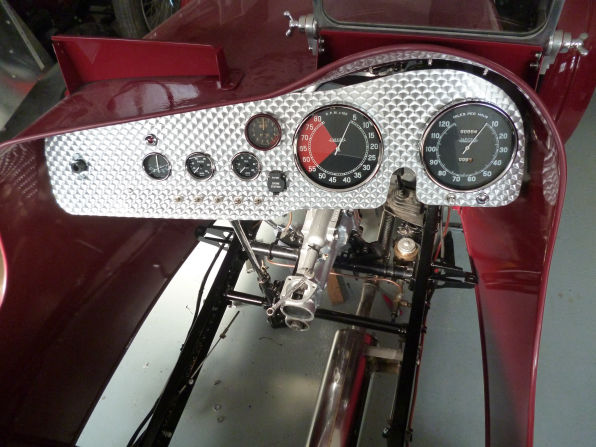 Engine-turned aluminium dash panel fitted with a rev counter, speedometer and a row of small gauges and switches.
